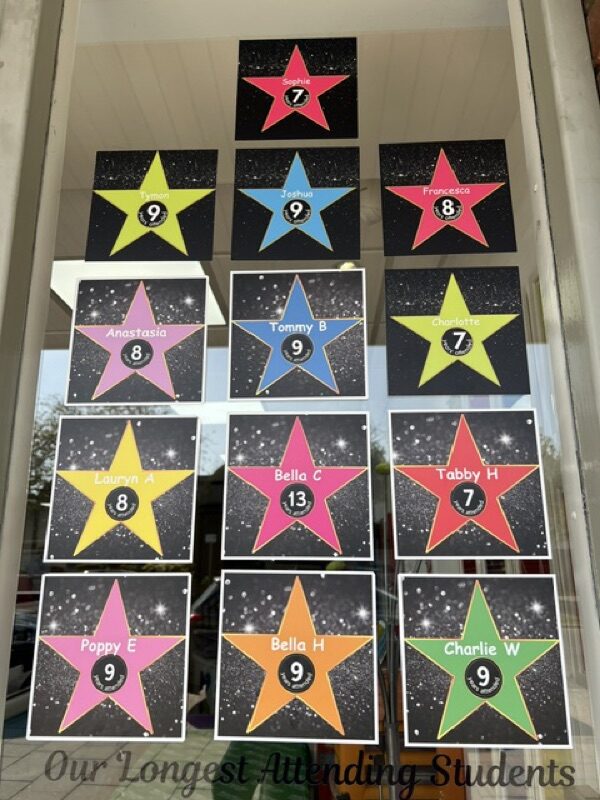 A window display of coloured stars, each naming a student and the number of years they have attended, under the heading Our Longest Attending Students