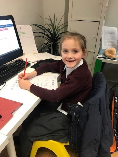 A primary school child working through a worksheet with a pencil at the centre